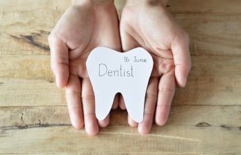 Hands holding a tooth cut from paper