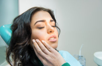 woman with toothache holds by cheek