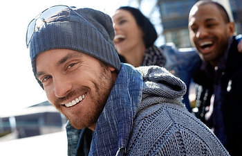 outdoor portrait of happy young man wearing scarf and smiling at camera, 